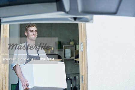 Caterer carrying box from kitchen, towards car