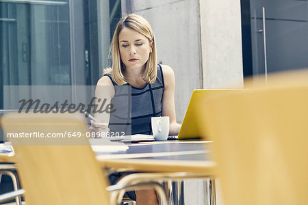 Young businesswoman writing at office desk