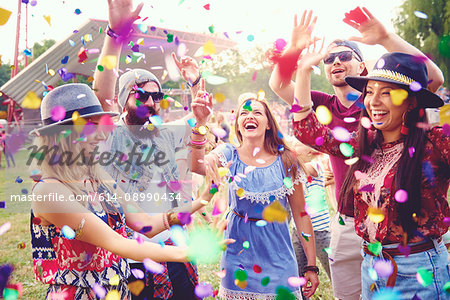 Young adult friends throwing confetti at festival