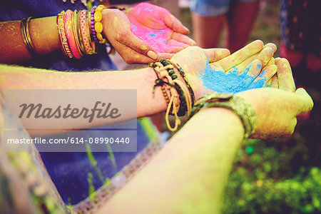 Pink and blue chalk cupped in young couples hands at festival