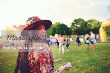 Portrait of young boho woman with handful of blue chalk powder at festival