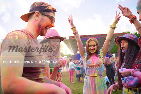 Young adult friends dancing covered in coloured chalk powder at festival