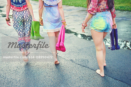 Waist down view of young women walking barefoot at festival