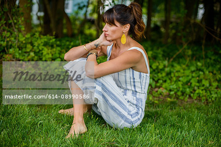 Mid adult woman sitting cross legged in garden