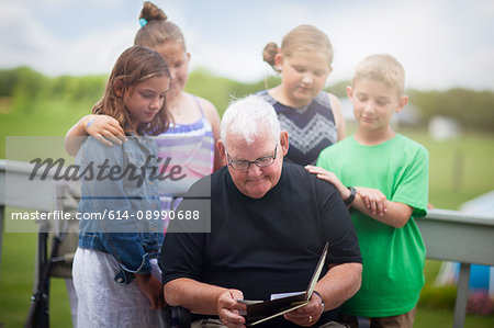 Grandfather surrounded by grandchildren giving him greeting card