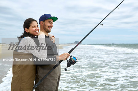 Young couple in waders sea fishing