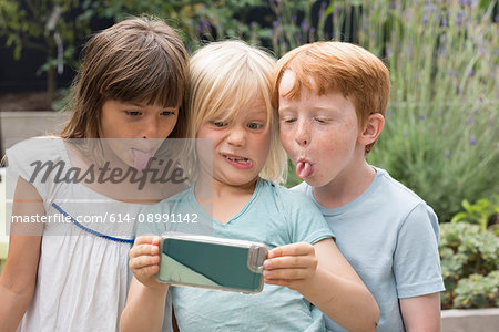Children sticking out tongue taking selfie