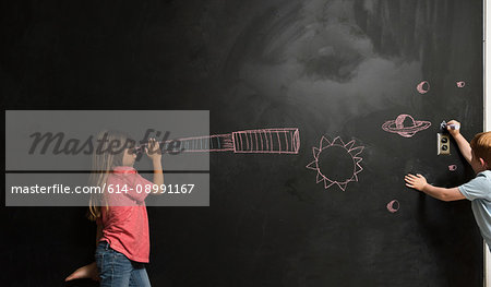 Girl looking through imaginary telescope drawn on blackboard