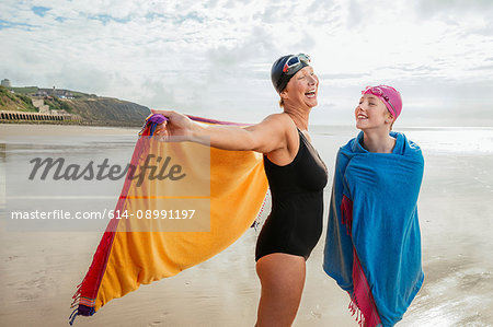 Mother and daughter standing on beach with shawls, Folkestone, UK