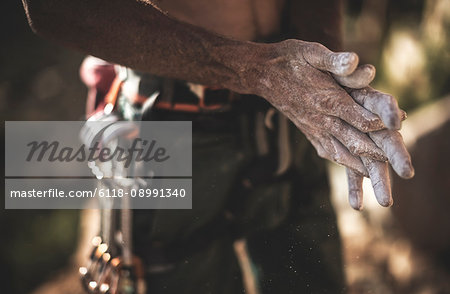 Close up of a climber spreading white chalk powder over his hands.