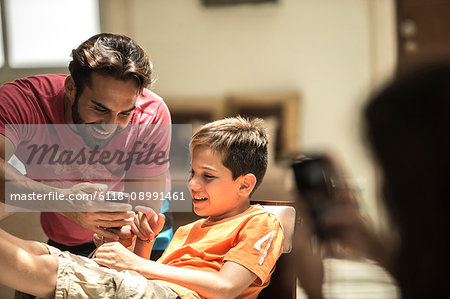 A man and a boy looking at a mobile phone screen.