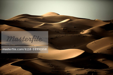 Desert landscape with sand dunes under a clear hazy sky.