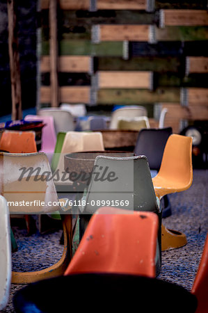 Interior of a building with worn plastic chairs around rusty metal tables.