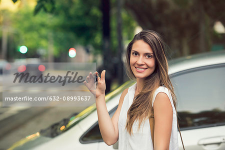 Young woman holding car keys, smiling, portrait