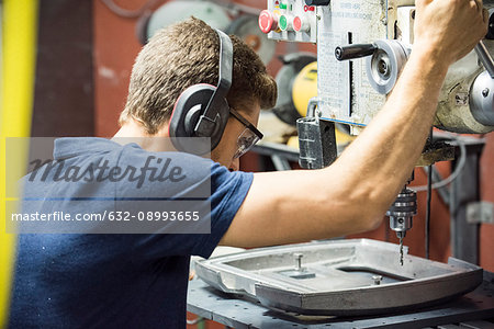 Machinist using drill in factory