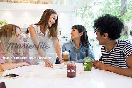 Waitress serving drinks to group of women in cafe
