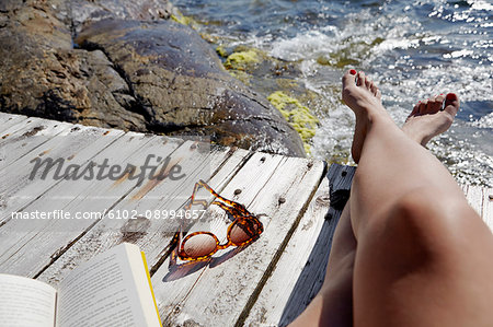 Low section of woman sun-bathing on jetty