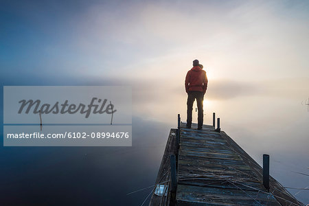 Man standing at the end of wooden pier