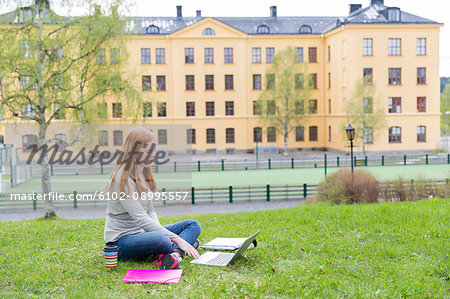 Teenage girl on lawn using laptop