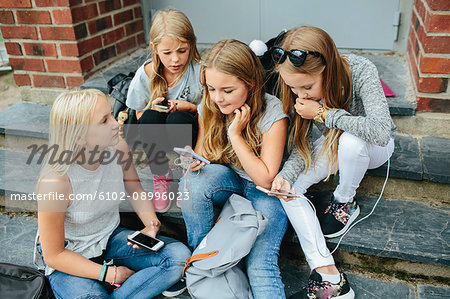 Girls sitting on steps and using cell phones