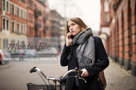 Young woman with bicycle on the phone