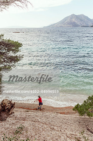 Boy throwing stones on beach