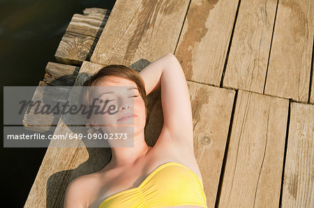 Young girl relaxing and sunning on pier