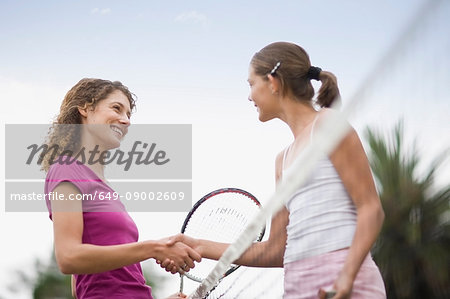 Girls shaking hands on tennis court