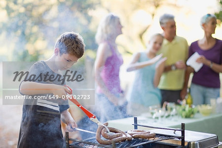 Boy barbecuing sausage outdoors Boy barbecuing sausage outdoors