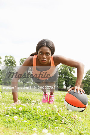 Woman doing push ups with basketball