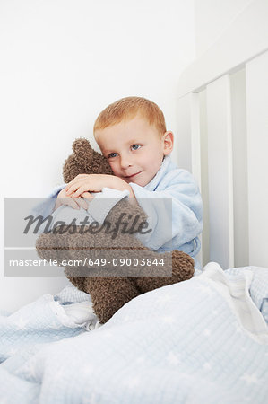 Boy hugging teddy bear in bed