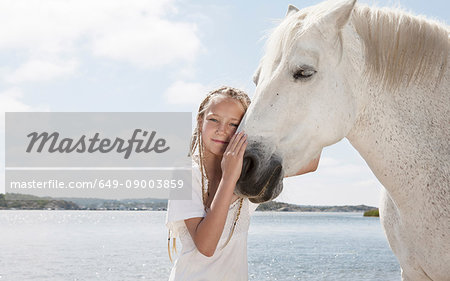 Girl petting horse on sandy beach