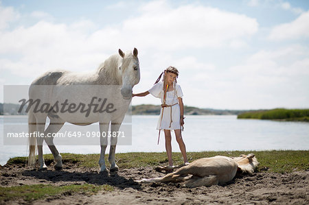 Girl petting horses on sandy beach