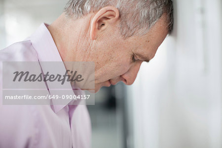 Businessman leaning forehead on wall