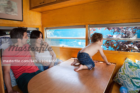 Boy on table in trailer home with parents