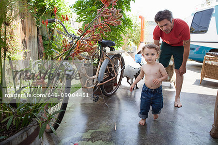 Son running on patio with father watching