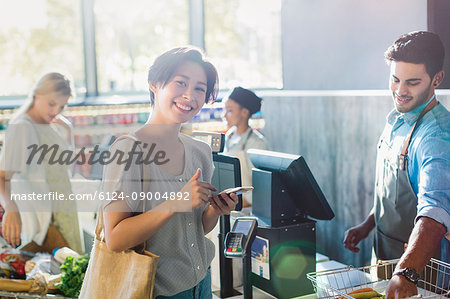 Portrait smiling young woman at grocery store checkout
