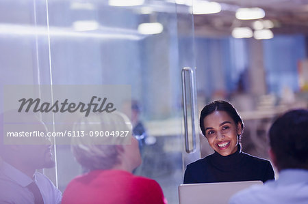 Smiling businesswoman using laptop in conference room meeting