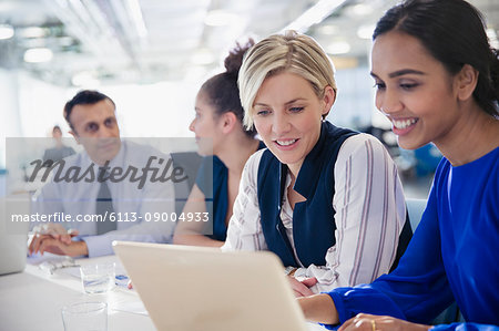 Businesswomen working at laptop in office meeting