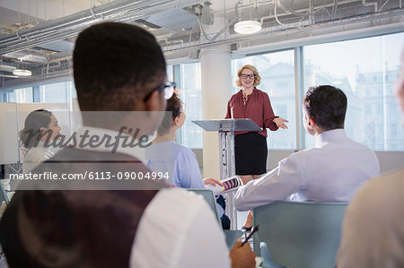 Businesswoman at podium leading conference presentation