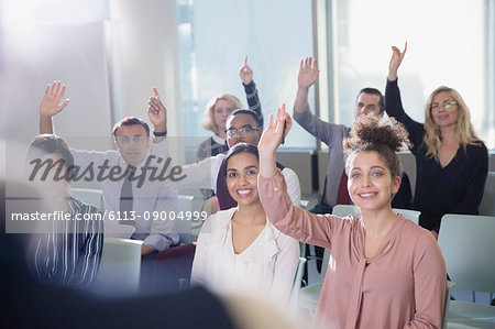 Smiling business people asking a question in conference audience