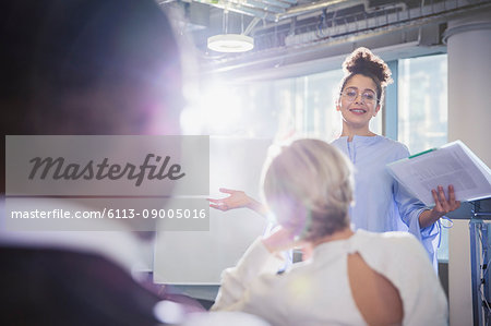 Businesswoman with paperwork leading conference room meeting