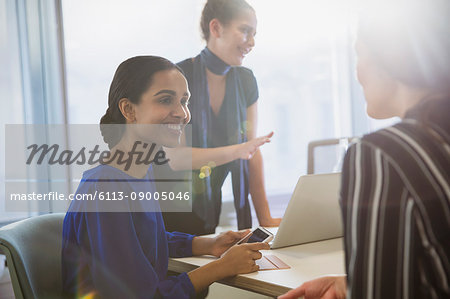 Smiling businesswomen talking in conference room meeting