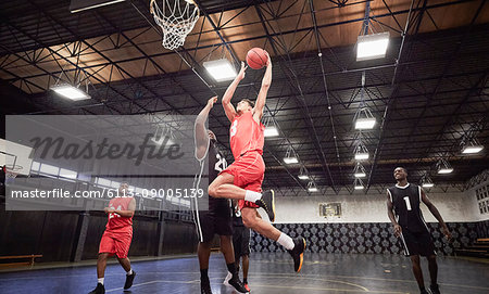 Young male basketball players playing basketball on court in gymnasium