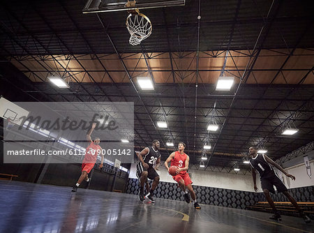 Young male basketball players playing basketball on court in gym
