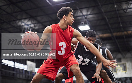 Young male basketball player dribbling the ball, playing game in gymnasium