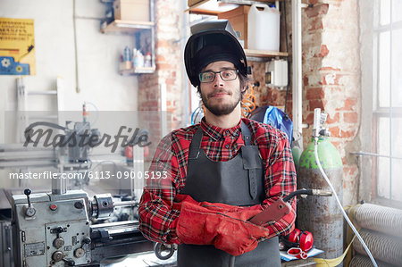 Portrait confident welder with welding torch in workshop