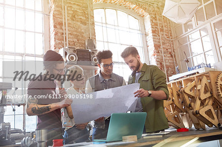 Designers examining blueprints in workshop