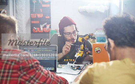 Computer programmers programming robotics in workshop