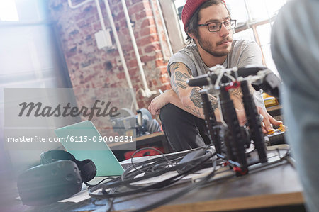 Male computer programmer programming electronics in workshop